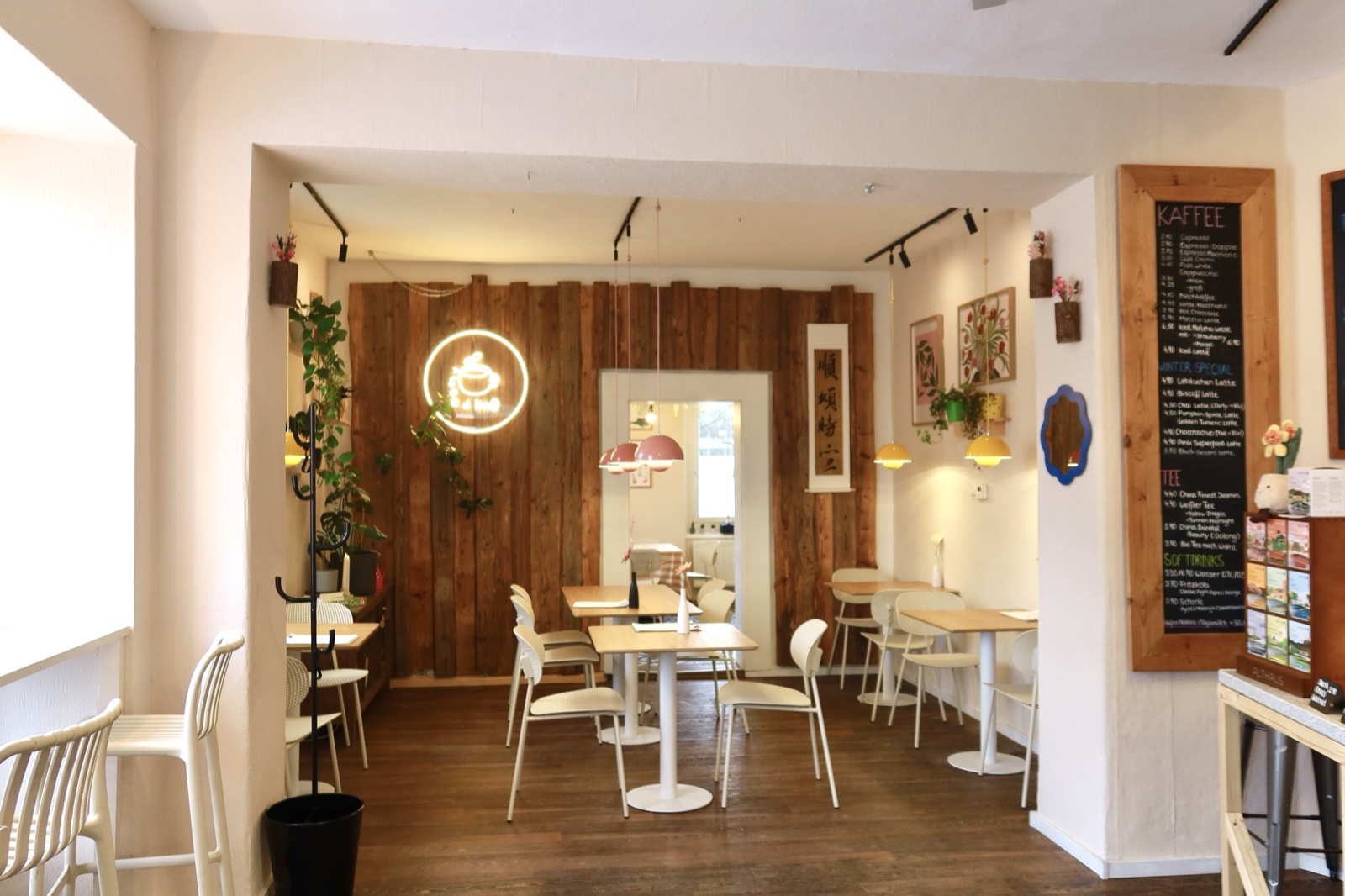 Innenraum von Café Seedling — Holzwand, Pflanzen, helle Tische
