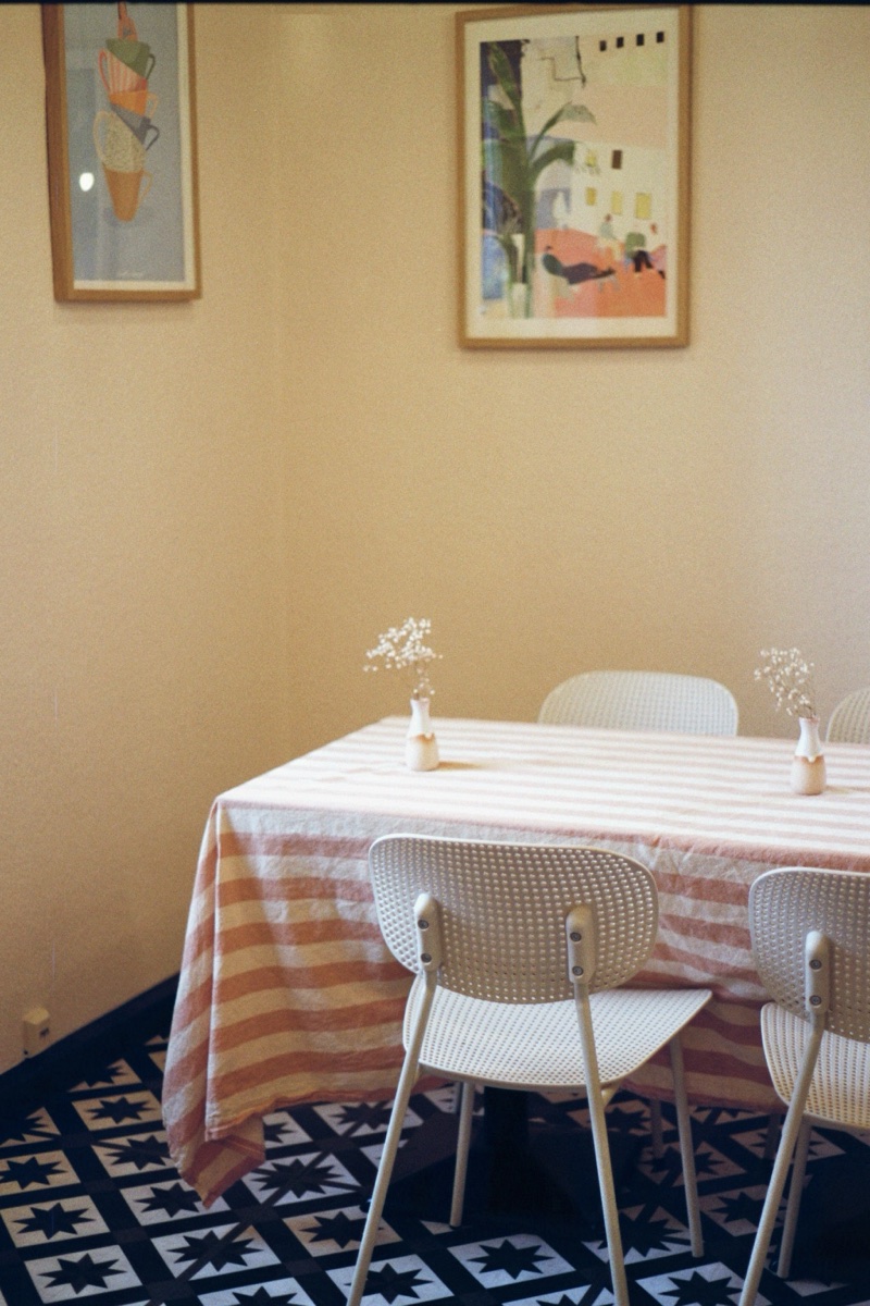 Tisch mit Streifentischdecke, Stühle und Kunstdrucke an der Wand